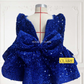 A royal blue sequined children's dress by house of claire displayed on a mannequin against a white decorative wall. The dress has a square neckline, puffed sleeves, and a tiered ruffled skirt. www.houseofclaire.com
