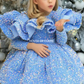 A young girl with blonde hair wearing a sparkly light blue sequined ballgown and a silver headband, posing in front of a decorated Christmas tree. The brand name 'HOUSE OF CLAIRE' is watermarked on the image.
Luxury Lavendar Blue Sparkle Baby Birthday Party Ball Gown Dress by house of Claire.
www.houseofclaire.com