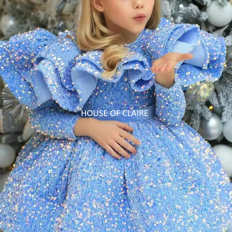A young girl with blonde hair wearing a sparkly light blue sequined ballgown and a silver headband, posing in front of a decorated Christmas tree. The brand name 'HOUSE OF CLAIRE' is watermarked on the image.
Luxury Lavendar Blue Sparkle Baby Birthday Party Ball Gown Dress by house of Claire.
www.houseofclaire.com